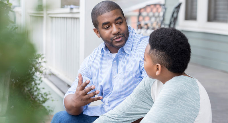 photo of a fatherly black man speaking to a young boy